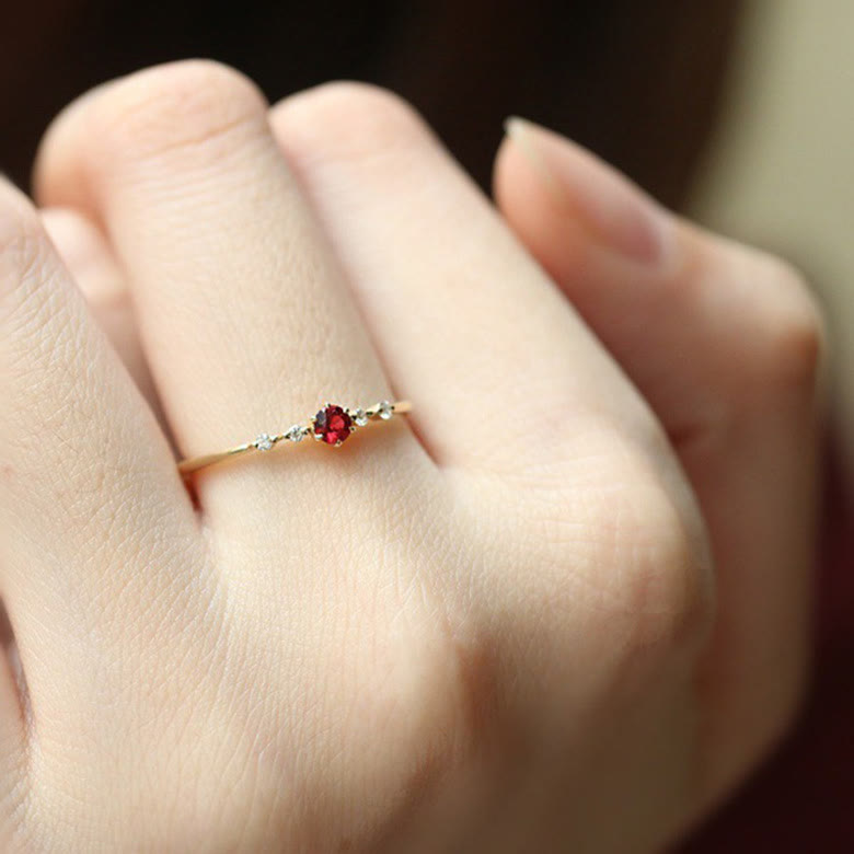 Dünner Goldring mit rotem Edelstein, eleganter Schmuck, Damenring, minimalistisches Design.