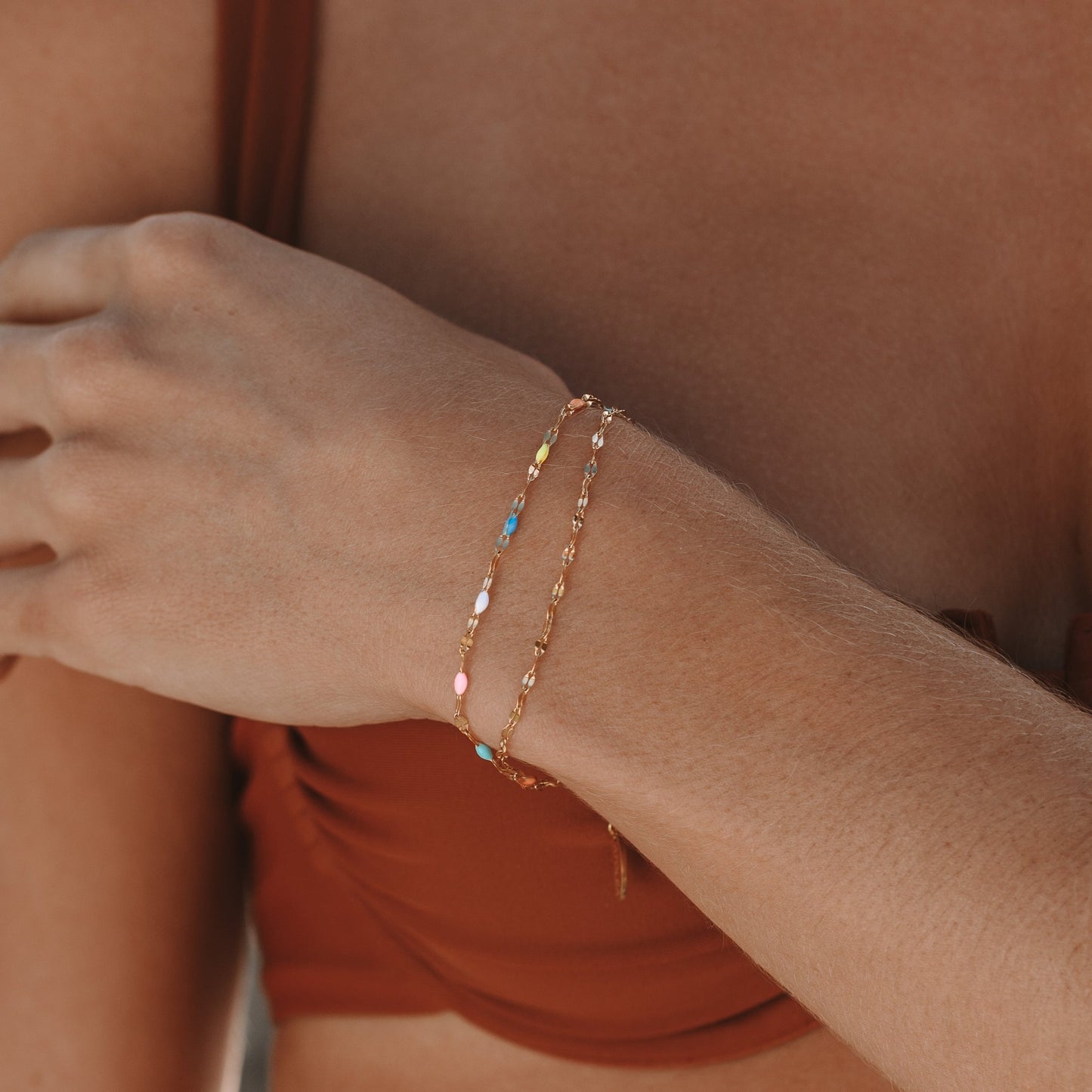 Frau trägt zweireihiges Regenbogen-Armband, goldfarben, bunte Perlen, modisches Accessoire.