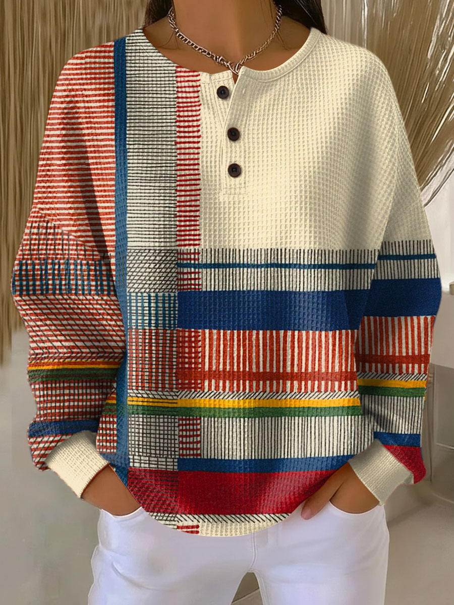 Getragener Pullover mit Knopfleiste, cremefarbener Brustpartie und bunten Streifen- und Blockmustern in Rot, Blau, Gelb und Grün. 6