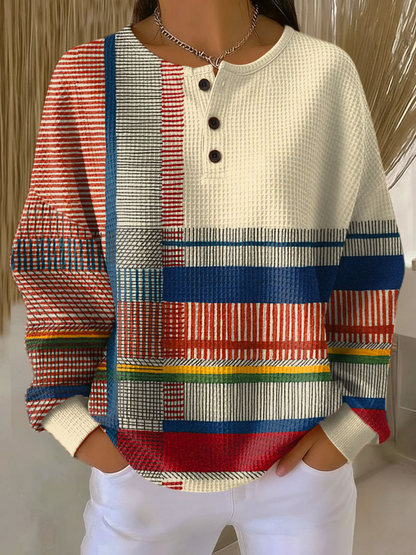 Getragener Pullover mit Knopfleiste, cremefarbener Brustpartie und bunten Streifen- und Blockmustern in Rot, Blau, Gelb und Grün. 6