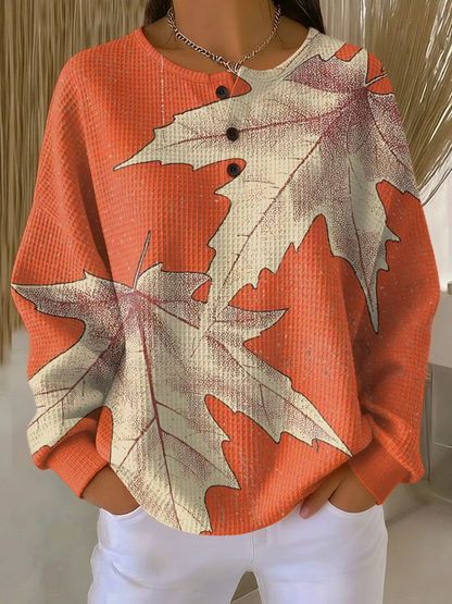 Orangefarbener Waffelstrick-Pullover mit Knopfleiste und großen cremefarbenen Ahornblättern als Motiv. 14