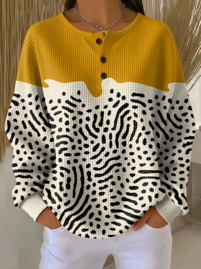 Getragener Pullover mit Knopfleiste: senfgelbe Schulterpartie, darunter cremefarbener Teil mit schwarzem Punkt- und Strichmuster. 13