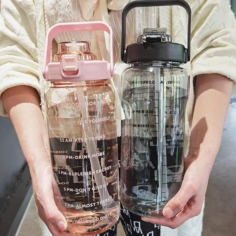 Zwei große Wasserflaschen, rosa und schwarz, mit Zeitmarkierungen, in Händen gehalten.