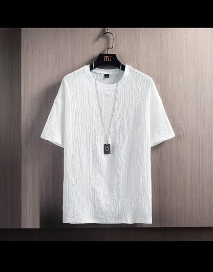 Weißes T-Shirt aus Baumwolle, kurzärmelig, strukturiert, auf Holzkleiderbügel hängend.