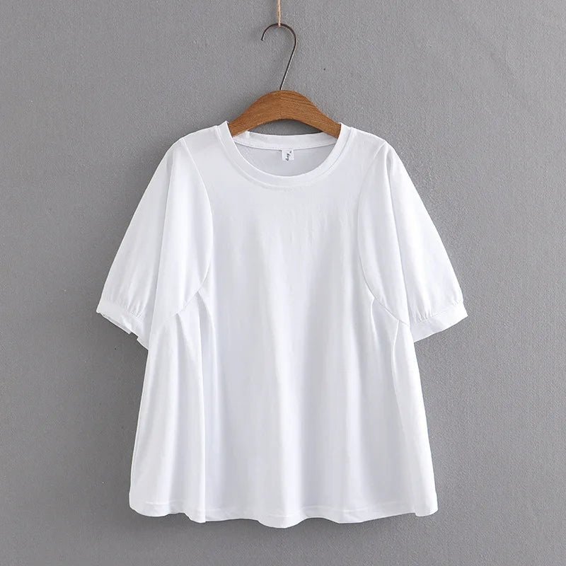 Weißes Damen-T-Shirt aus Baumwolle, kurzärmelig, auf Holzkleiderbügel vor grauer Wand.