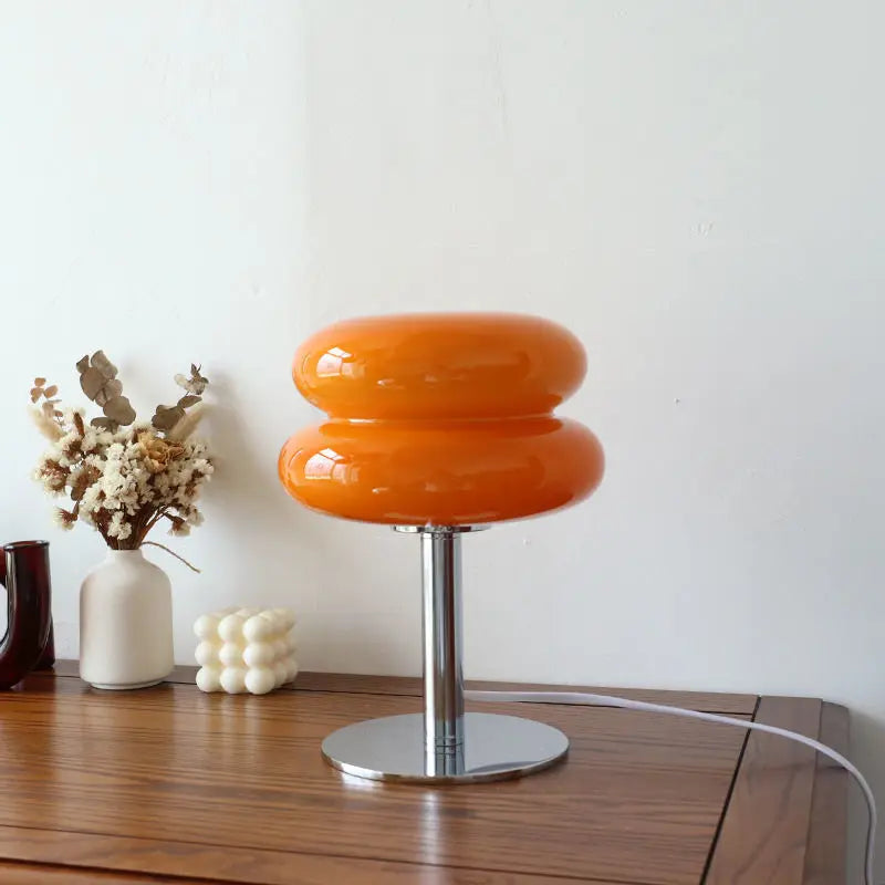Orangefarbene Tischlampe aus Glas auf Holztisch, moderne Dekoration, minimalistisch.
