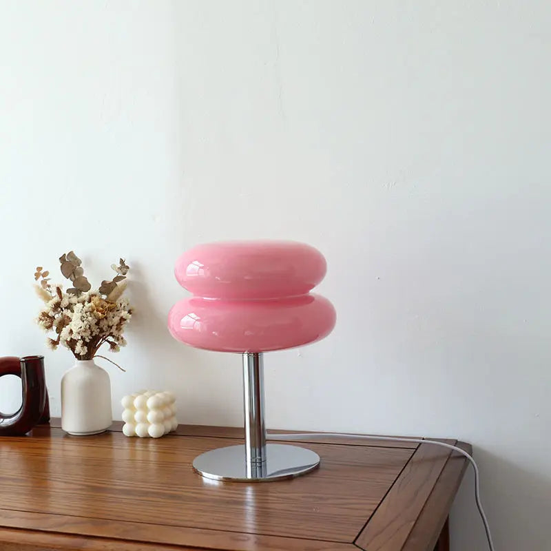 Rosa Tischlampe aus Glas auf Holztisch, moderne Dekoration, minimalistisches Design.