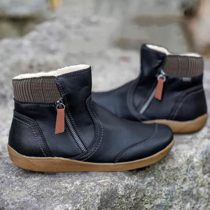 Schwarze Stiefeletten mit orangebrauner Reißverschlusslasche und kariertem Schaftrand, Seitenansicht beider Schuhe auf grauem Fels. 2