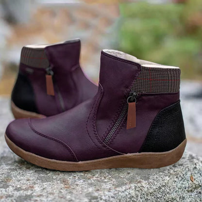 Violette Stiefeletten mit schwarzer Fersenkappe, Reißverschluss an der Seite und kariertem Schaftabschluss, auf einem Steinblock im Freien. 4
