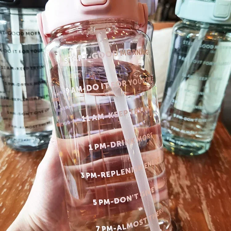Durchsichtige Wasserflasche mit Zeitmarkierungen, rosa Deckel, motivierende Trinkziele.