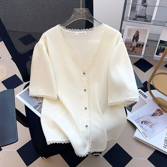 Weiße Strickjacke mit Knöpfen, V-Ausschnitt, Spitzenbesatz, Damenmode, elegant, auf Stuhl.