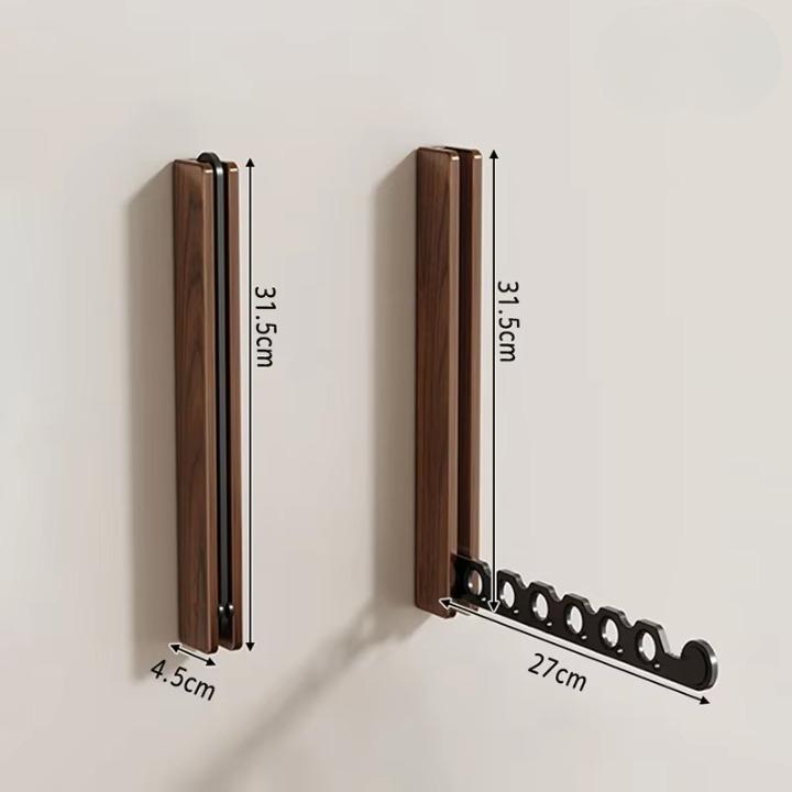 Maßdarstellung der dunklen Wandgarderobe eingeklappt und ausgeklappt, mit eingezeichneten Maßen für Höhe, Tiefe und Länge des Arms. 10