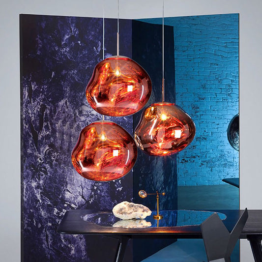 Drei moderne, kupferfarbene Pendelleuchten über einem Tisch, stilvolles Innendesign.