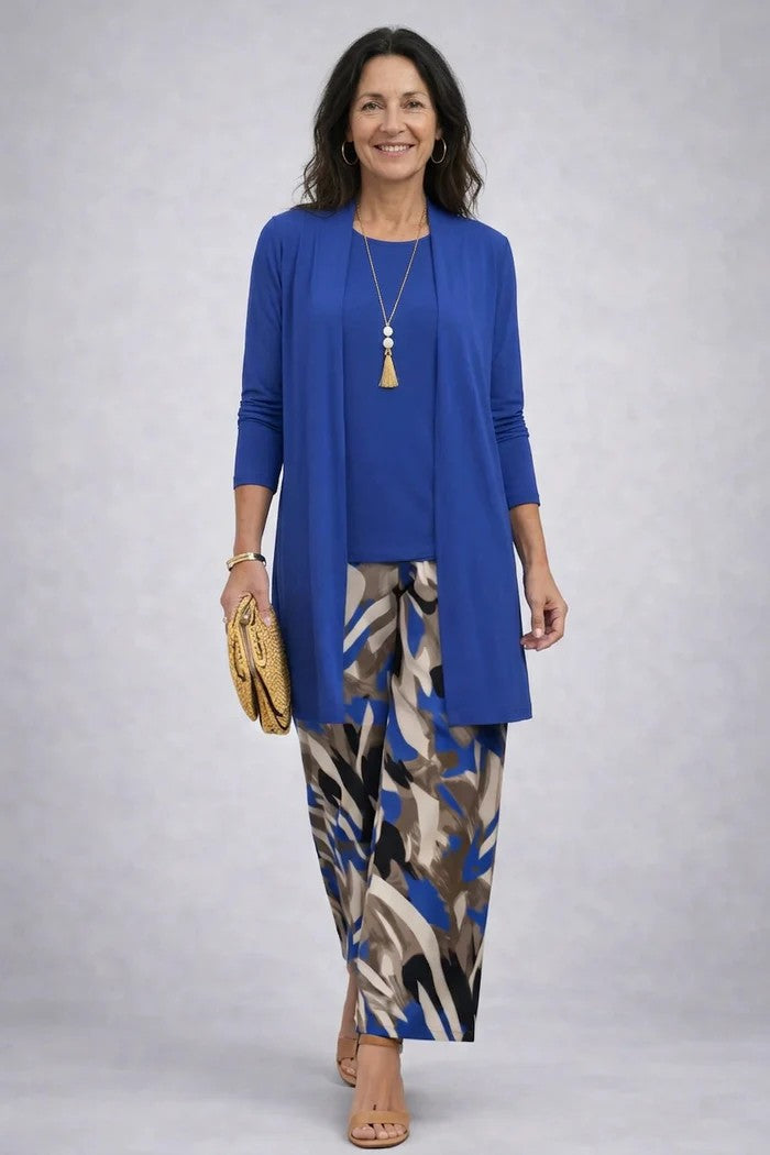 Frau im Set mit königsblauem Cardigan und Oberteil, dazu weite Hose mit abstraktem blau-braunem Muster, Clutch in der Hand. 9