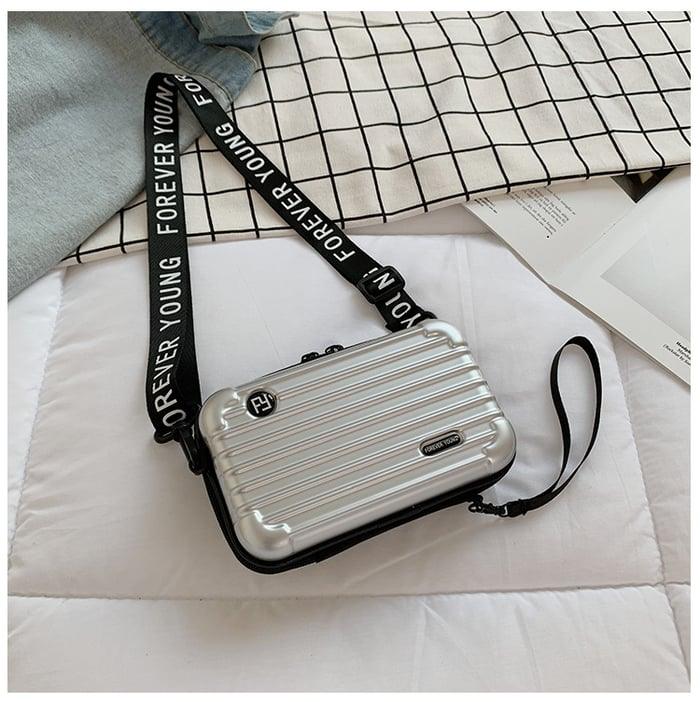 Silberne Mini-Koffer-Handtasche für Damen, mit schwarzem "Forever Young" Schultergurt.