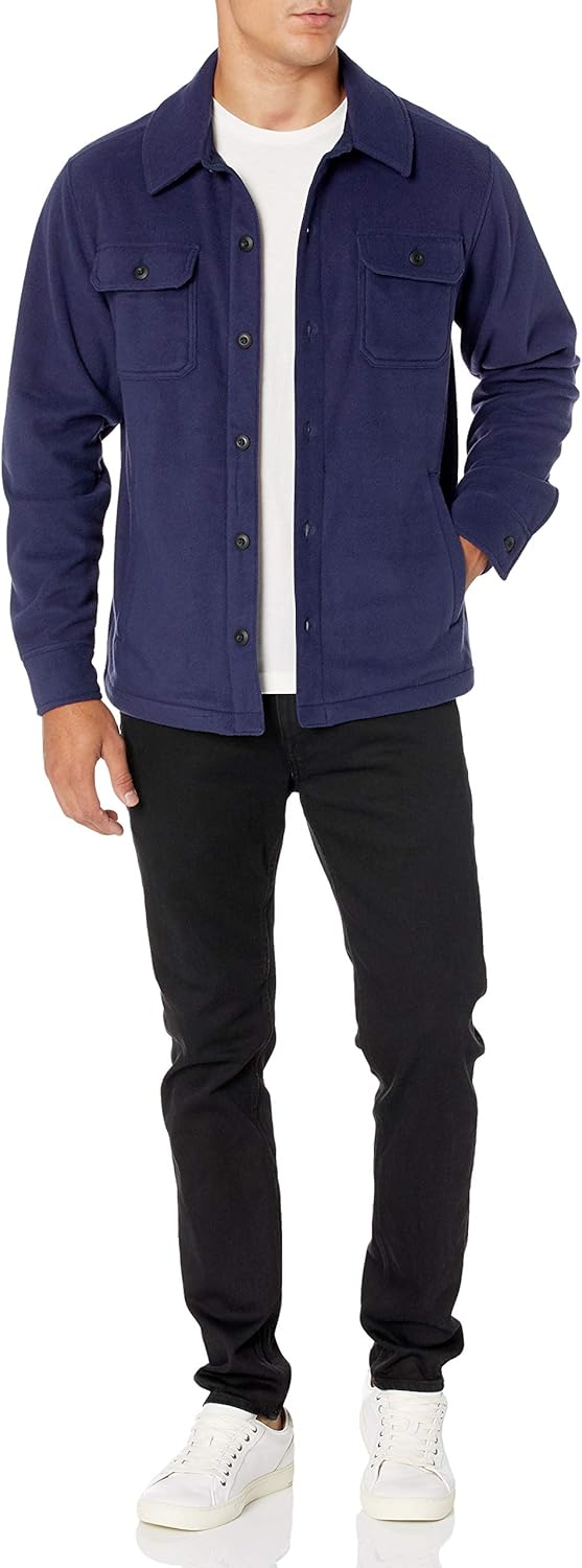 Mann in dunkelblauer Fleecejacke, weißem T-Shirt, schwarzer Hose und weißen Sneakern.
