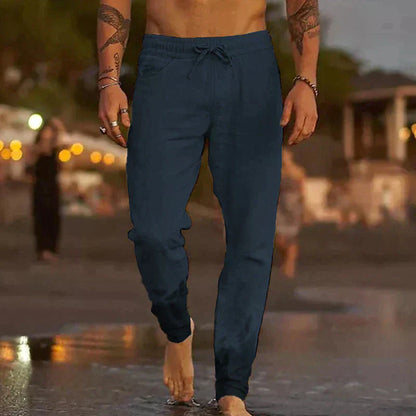 Mann in dunkelblauer Jogginghose am Strand, lässige Herrenmode, Freizeitkleidung.