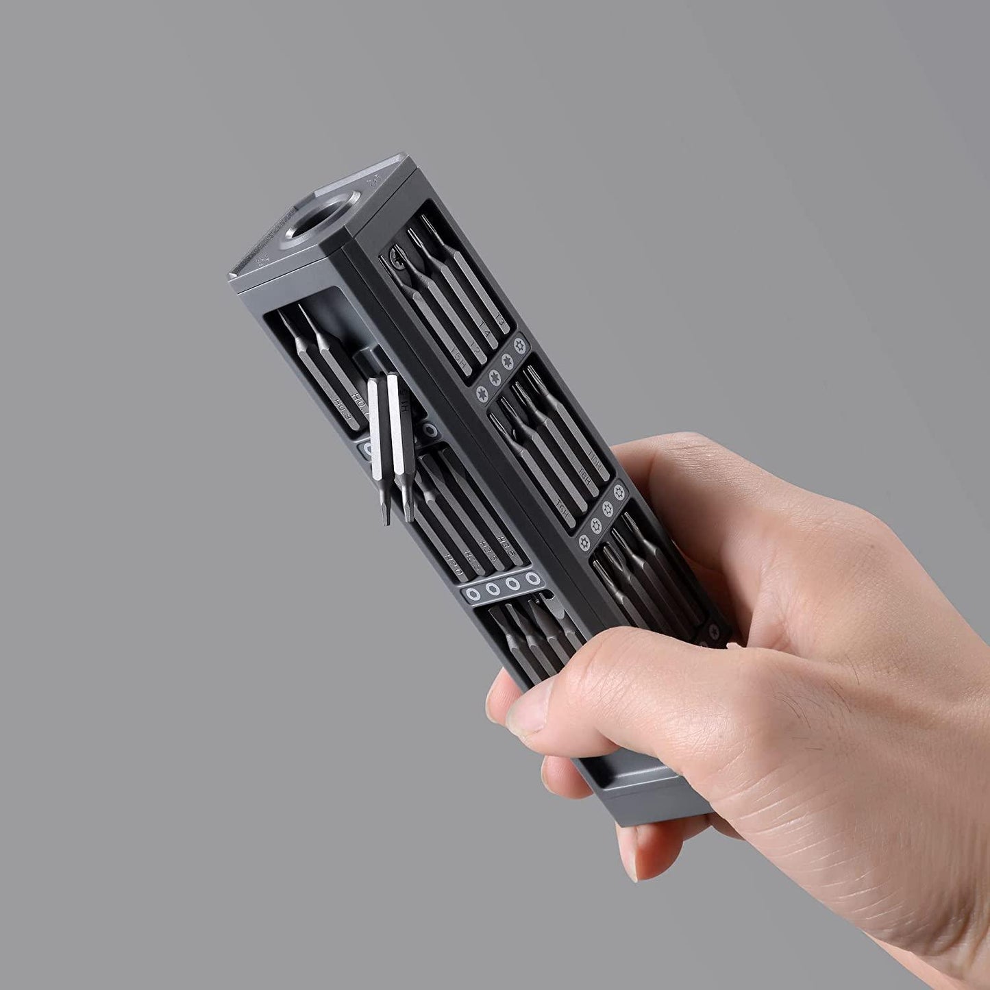 Hand hält graues Schraubendreher-Set, magnetisch, kompakt, vielseitig, Werkzeug, Heimwerker.