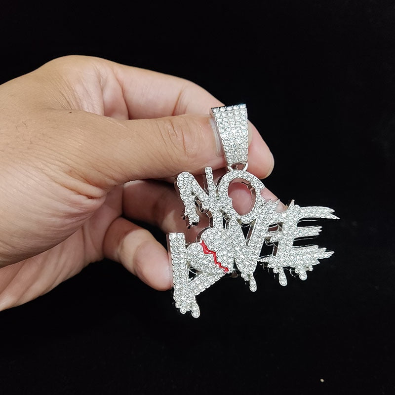 Hand hält silbernen "No Love" Anhänger mit Strasssteinen, Schmuck, Hip-Hop-Stil.
