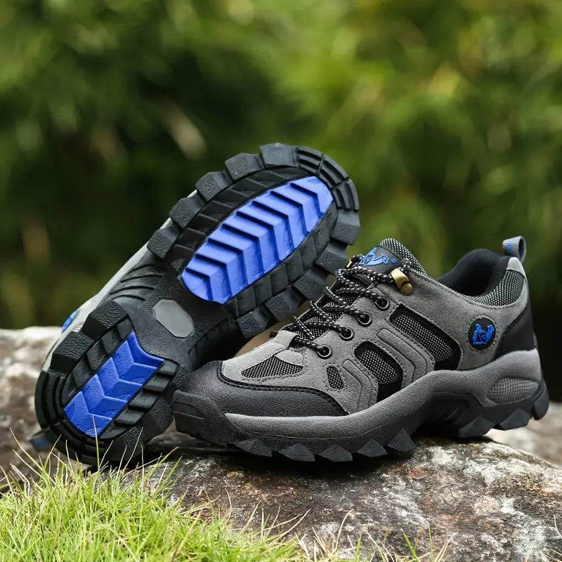 Graue Wanderschuhe mit blauen Sohlen, Outdoor-Schuhe, rutschfest, robust, Herren, Naturhintergrund.