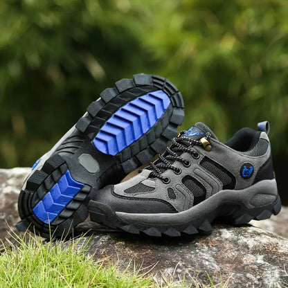 Graue Wanderschuhe mit blauen Sohlen, Outdoor-Schuhe, rutschfest, robust, Herren, Naturhintergrund.