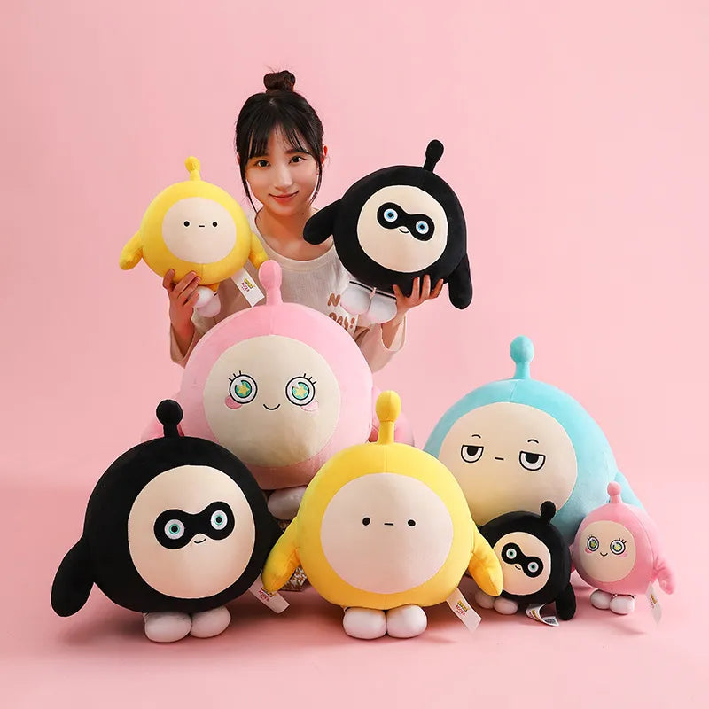 Frau mit bunten EggyGo Plüschfiguren, gelb, schwarz, blau, rosa, auf rosa Hintergrund.