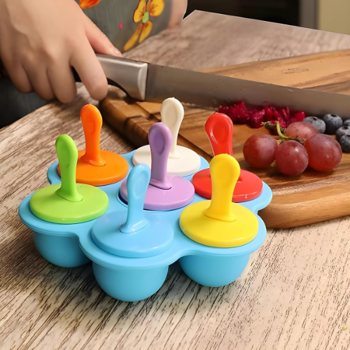 Bunte Silikon-Eisformen mit Griffen auf Holztisch, ideal für hausgemachtes Eis am Stiel.