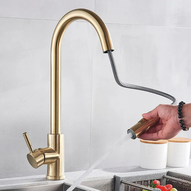 Goldfarbener Wasserhahn mit herausgezogener Handbrause am Schlauch, eine Hand mit Armband hält sie, während Wasser ausströmt. 3