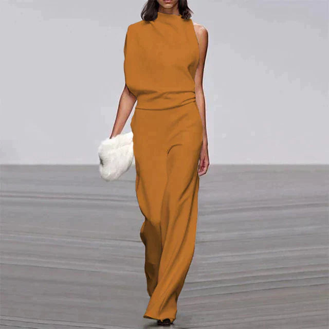 Frau in eleganter, ärmelloser, senfgelber Jumpsuit mit weitem Bein, hält weiße Clutch.