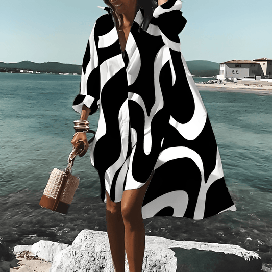 Frau in schwarz-weißem, knielangem Print-Kleid am Strand, Sommermode, stilvoll.