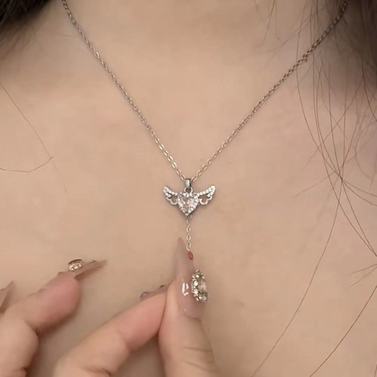 Silberne Halskette mit Engelsflügel-Anhänger, Damenmode, eleganter Schmuck, Nahaufnahme.