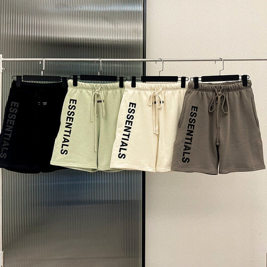 Vier Essentials-Shorts in Schwarz, Creme, Beige und Grau auf Kleiderstange.