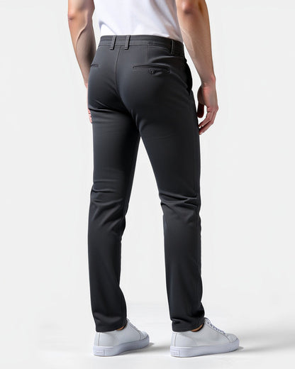 Rückansicht der anthrazitfarbenen Chino mit Paspeltaschen am Gesäß, Gürtelschlaufen und weißen Sneakern. 8