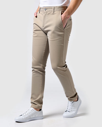 Beige Chino in seitlicher Ansicht, kombiniert mit weißem T-Shirt und weißen Sneakern, Hände in den Taschen. 14