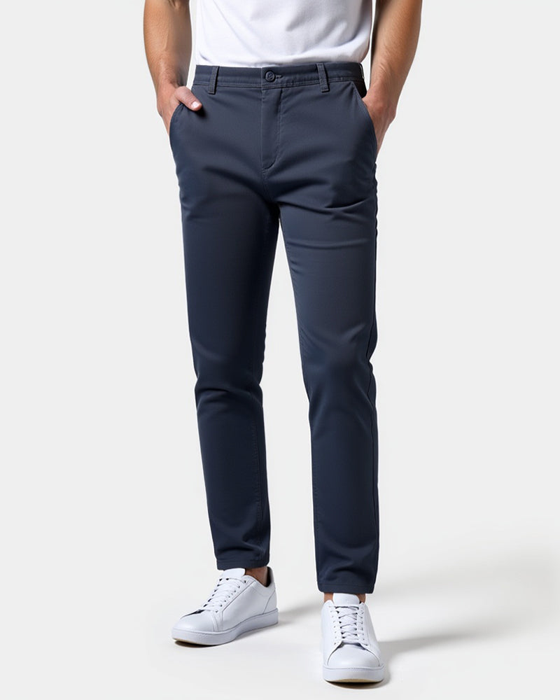 Marineblaue Chino von vorn mit weißem T-Shirt und weißen Sneakern, beide Hände in den Seitentaschen. 15