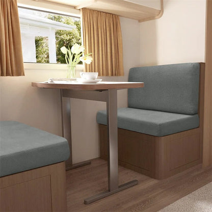 Wohnmobil-Essbereich mit grauen Polstern, Holztisch, Vorhängen und Blumen, gemütliches Interieur.
