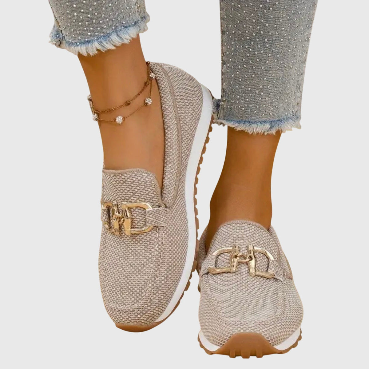Beigefarbene Netzstoff-Slipper mit goldener Spange, von einer Frau mit Fußkettchen und Strass-Jeans getragen 1