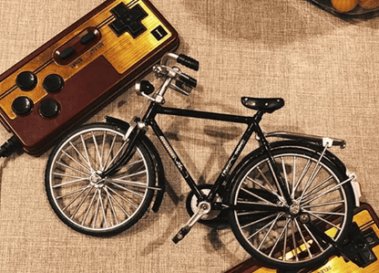 Spielzeugfahrrad aus Metall auf Retro-Gaming-Controller, Vintage-Dekor, Sammlerstück.
