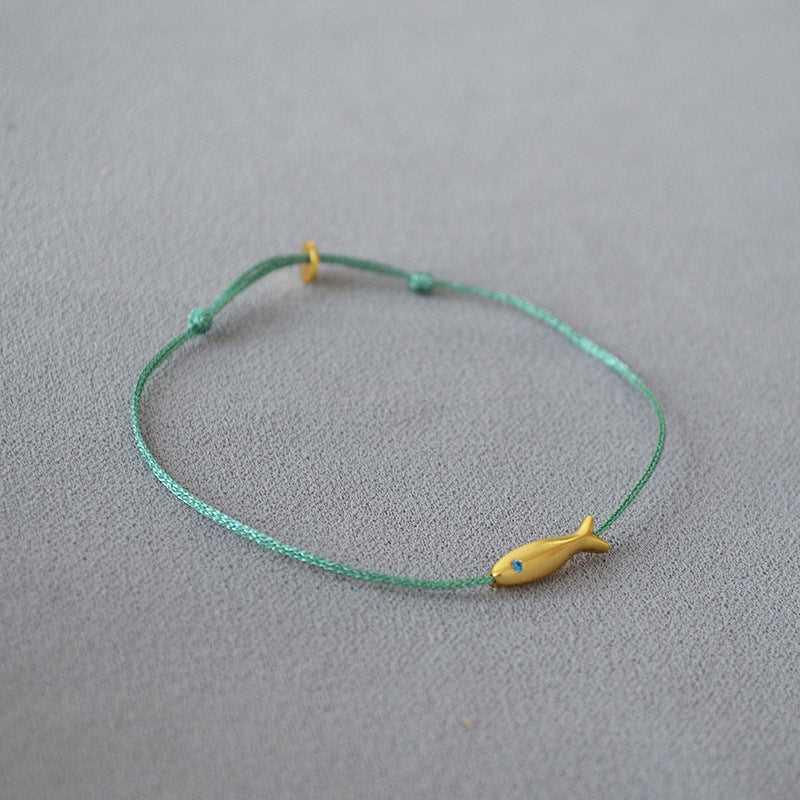 Grünes Armband mit gelbem Fischanhänger, handgefertigt, minimalistisches Schmuckdesign.