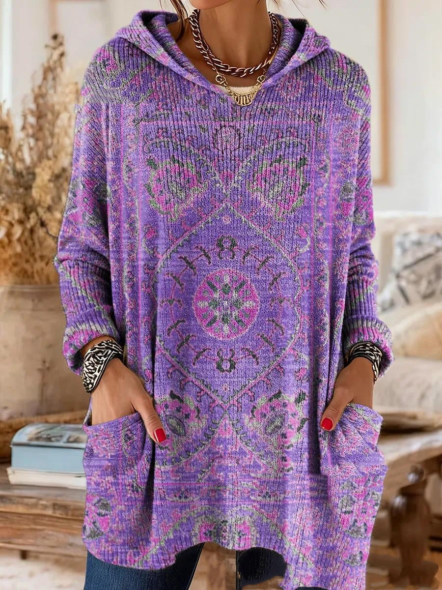Von einem Model getragene Tunika in Lila mit rosa-grünem Ornamentmuster, Kapuze, langen Ärmeln und Taschen. 2