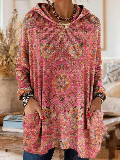 Von einem Model getragene Tunika in Pink mit orangefarbenem Ornamentmuster, locker geschnitten mit Kapuze und Taschen. 6