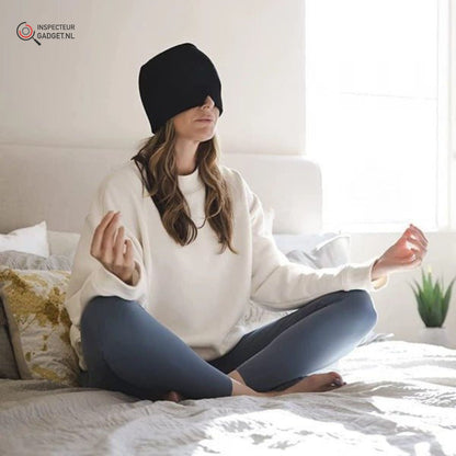Frau meditiert im Schlafzimmer, trägt schwarze Augenmaske, weiße Pullover, blaue Leggings.