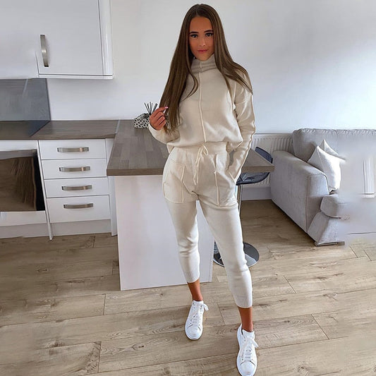 Frau in cremefarbenem Jogginganzug, Kapuzenpullover, Jogginghose, weiße Sneaker, Wohnzimmer.