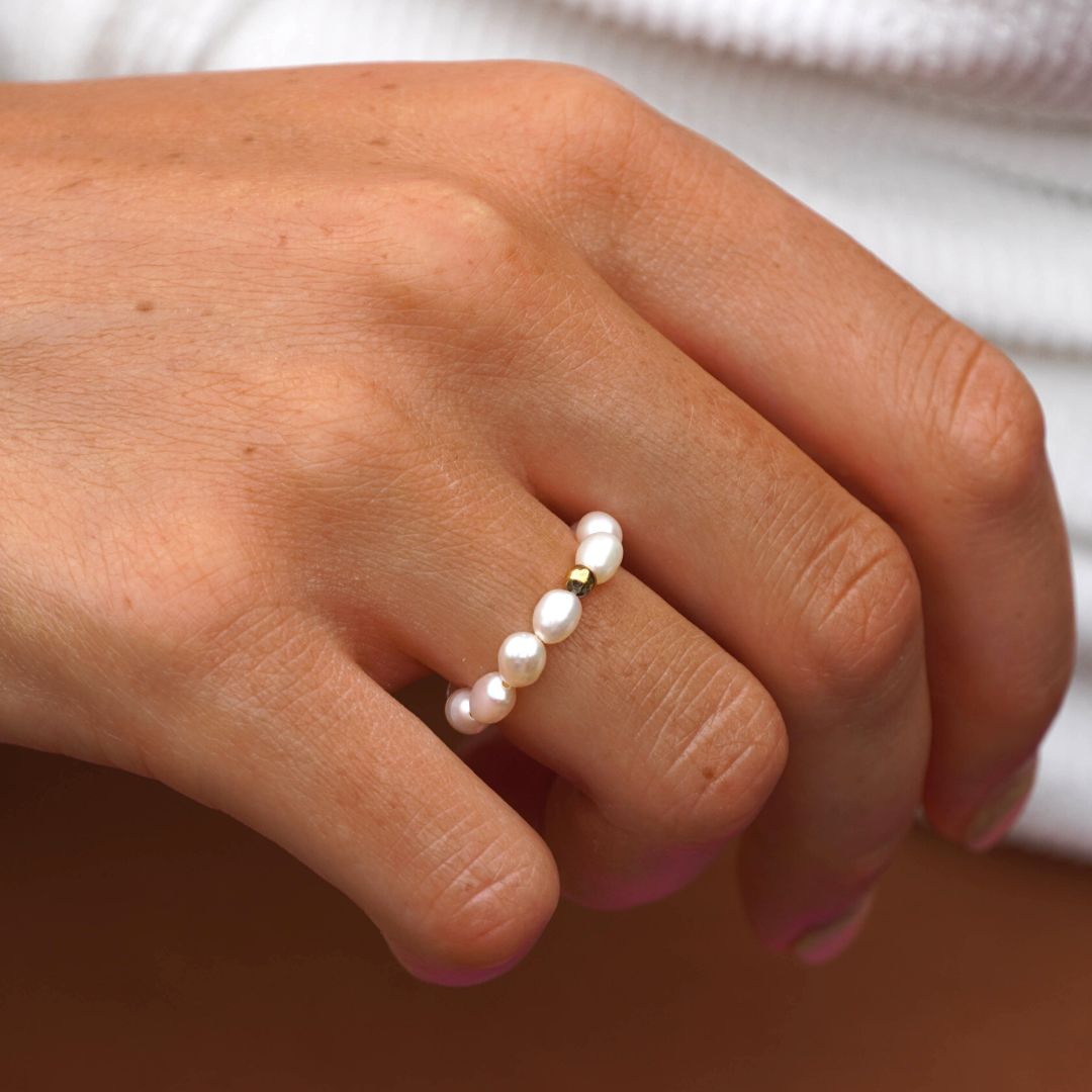 Hand mit Süßwasserperlenring, goldene Fassung, eleganter Schmuck, Damenmode, Nahaufnahme.