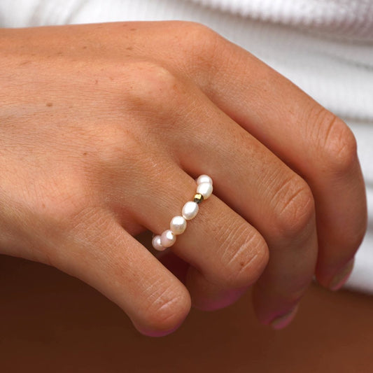 Hand mit Süßwasserperlenring, goldene Fassung, eleganter Schmuck, Damenmode, Nahaufnahme.