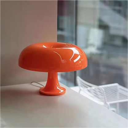 Orange Tischlampe aus Glas, modernes Design, auf weißem Tisch vor Fenster, Innenraumbeleuchtung.