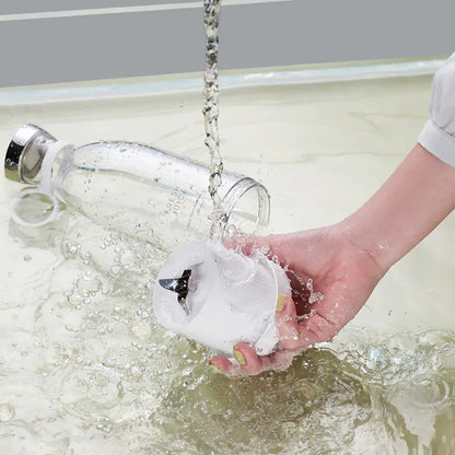 Hand wäscht weißen Mixeraufsatz, Glasflasche im Hintergrund, Wasser fließt, Küchengerät Reinigung.