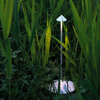 Moderne Gartenlampe in Pilzform, weiß, LED, energiesparend, zwischen hohen Grashalmen.