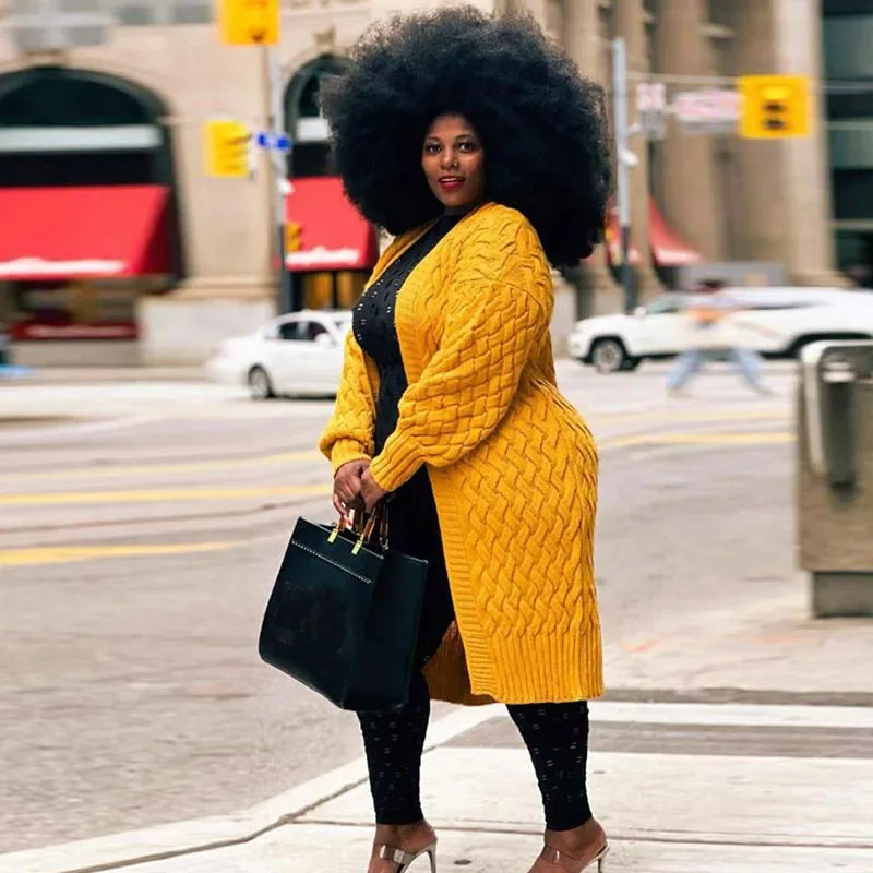 Frau in gelbem Strickmantel mit großer Afro-Frisur, schwarze Handtasche, Stadtstraße.