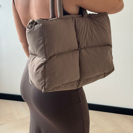 Frau mit brauner Stepphandtasche, modisch, elegant, aus Stoff, ideal für den Alltag.